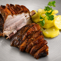 Eine Portion AUMAERK-Stelze „Crack Leg“ mit knuspriger Haut und saftigen Schichten wird neben gekochten Kartoffelscheiben, garniert mit Petersilie, auf einem silberfarbenen Teller angerichtet – perfekt zubereitet nach der AUMAERK-Methode.