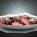 AUMAERKs Schweinsbackerl im „Royal Cheek Sixpack“ – zarte, saftige Schweinebacken mit rosa Mitte und knusprig gebräunten Rändern, dampfend auf einem blauen Keramikteller serviert, für eine frisch zubereitete, küchenfertige Präsentation.