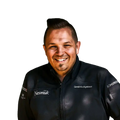Ein lächelnder Mann mit kurzen dunklen Haaren, der eine schwarze Jacke mit verschiedenen Logos, darunter AUMAERK und der Name Gerald-Hochgatterer, trägt, steht vor einem schlichten weißen Hintergrund.