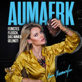 Eine Frau in einer goldenen Bluse hält ein Stück Fleisch in die Höhe und sitzt mit einem Getränk an einem Tisch. In blauer Schrift ist der Markenname „AUMAERK“ zu sehen, während in weißer Schrift auf Deutsch steht: „Feinstes Fleisch, das immer gelingt! Perfekt als Geschenk: Mit einem Gutschein ‚Imperial‘ von AUMAERK Premiumqualität erleben und Freude schenken!“.