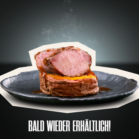 Ein saftiges Schweinsbackerl „Royal Cheek“ von AUMAERK wird in Scheiben geschnitten auf einem dunklen Teller präsentiert, wobei aufsteigender Dampf die durch die AUMAERK-Methode erzielte Zartheit unterstreicht. Darunter erscheint der deutsche Text „BALD WIEDER ERHÄLTLICH!“, was so viel bedeutet wie „Bald wieder erhältlich!“.